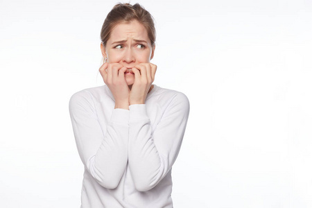 金发和灰色的眼睛咬着指甲,恐惧地站在那里,担心和紧张的感觉害怕