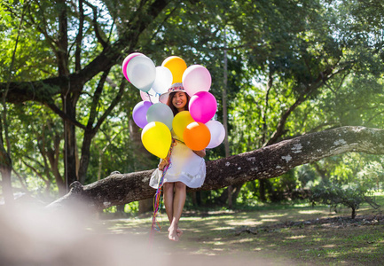 年轻的少女坐在树上，手里拿着气球