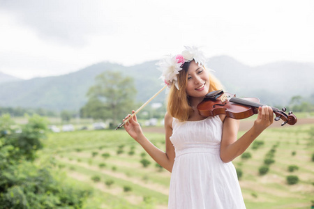 年轻的嘻哈音乐家女子拉小提琴在大自然户外生活背后的山。