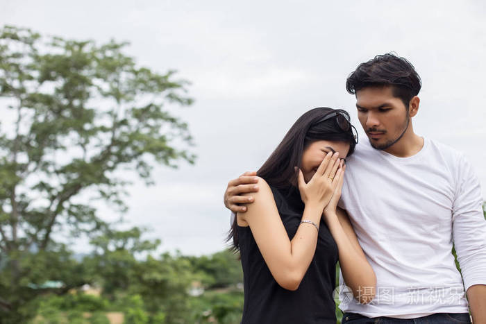 年轻英俊的男朋友拥抱他的女朋友她又伤心又难过