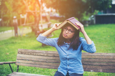 时髦迷人的女孩在公园放松，而阅读书籍享受周围的自然。