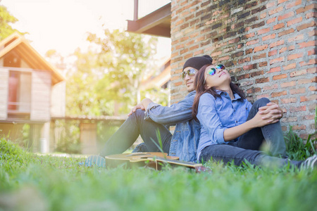 时髦的男人为他的女朋友在户外对着砖墙玩吉他。