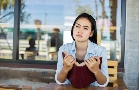 时髦迷人的女孩在公园放松，而阅读书籍享受周围的自然。