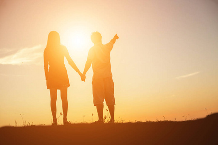 想要一个拥抱一个男人和女人手拉手一起走路的轮廓.照片