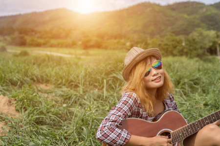 年轻的时髦女孩坐着弹吉他唱歌。