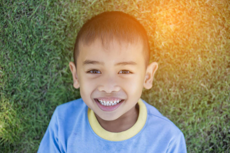 快乐的穆拉托男孩正微笑着享受收养的生活。 小男孩在自然公园或户外的肖像。 幸福家庭或成功收养或养育子女的概念。