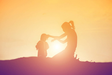 母亲鼓励她的女儿在日落时走出阴影。
