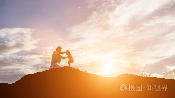 母亲鼓励她的女儿在日落时走出阴影