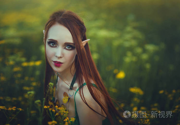 一个红头发的女孩精灵的肖像, 穿着绿色的泳装, 在黄色的花朵上摆姿势