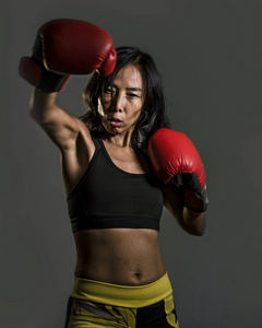特写照片年轻的适合亚洲的中国女人在健身顶部和拳击手套坏女孩的态度，愤怒和挑衅的战斗和战斗训练在孤立的黑暗背景。
