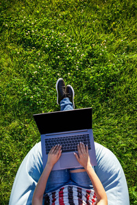 顶部视图。在笔记本电脑上工作的妇女与空白黑空屏幕在绿色草阳光草坪公园复制空间在户外