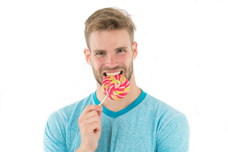 强壮的牙齿。男人拿着棒糖家伙吃巨型彩色棒糖分离白色背景。男人猪鬃喜欢甜食。过量的糖会导致龋齿的发展。牙齿护理与健康概念