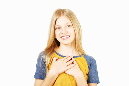 年轻漂亮，高兴的十几岁女孩，金发，穿着黄色棒球T恤，蓝色袖子。 美丽的女孩微笑的手掌心在胸前站在孤立的白色背景复制空间。
