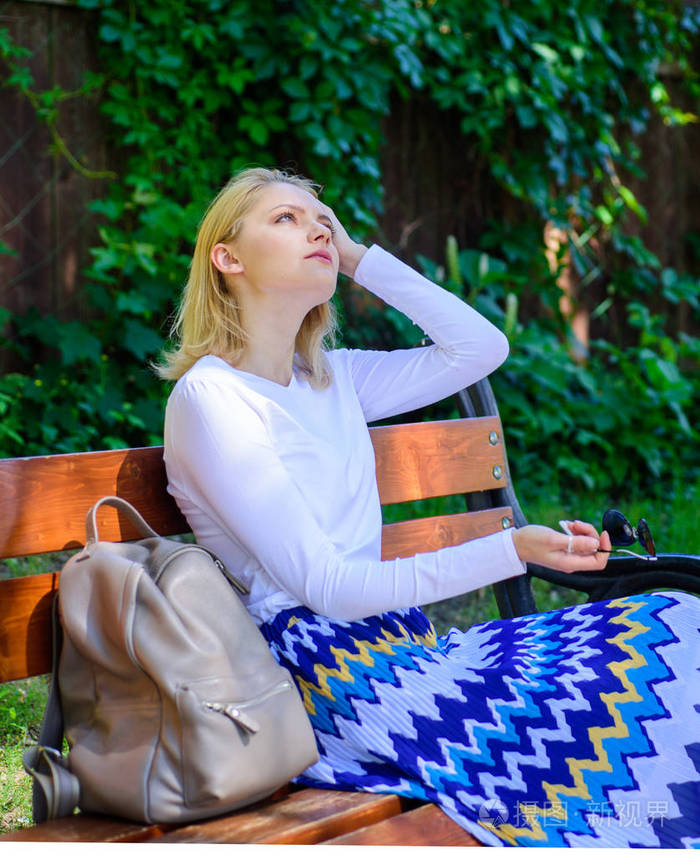 女孩坐板凳放松在阴影绿色自然背景女金发女郎在公园休息放松为什么你