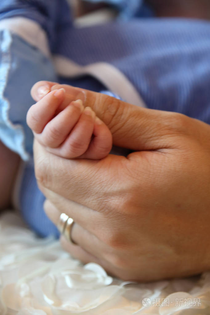 父母牵着新生婴儿的手