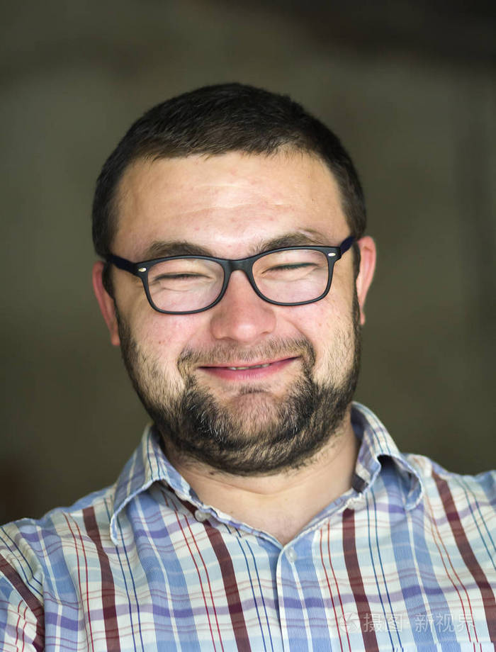 英俊的胡须,黑发,聪明的现代年轻人,戴着短发型的眼镜,和蔼的黑眼睛