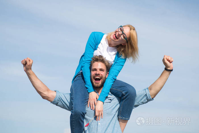 男人扛着女朋友的肩膀, 天空的背景.情侣相爱享受自由阳光明媚的一天