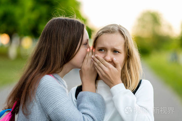 两个女孩朋友女生学生在夏天的城市告诉朋友耳朵一个秘密真的惊喜的