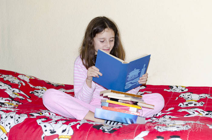 可爱的小女孩坐在床上看书