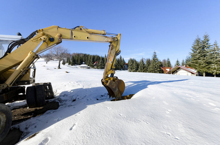 工业挖掘机在冬季积雪施工现场装载土料