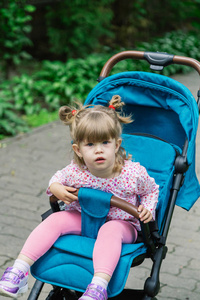 小女孩坐在婴儿车在一个美丽的公园