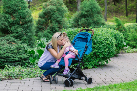 母亲在公园里推着婴儿推车走路照片