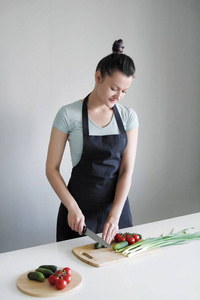 厨房围裙里的女人在木板上切蔬菜