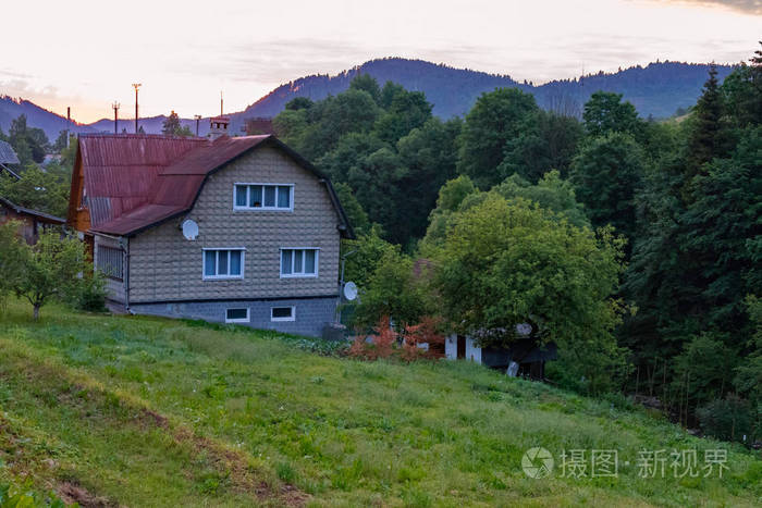 森林和山脉前的乡村三层房子