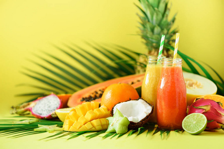 鲜黄色芒果多汁木瓜和菠萝, 芒果, 橙果冰沙在两个罐子的黄色背景.