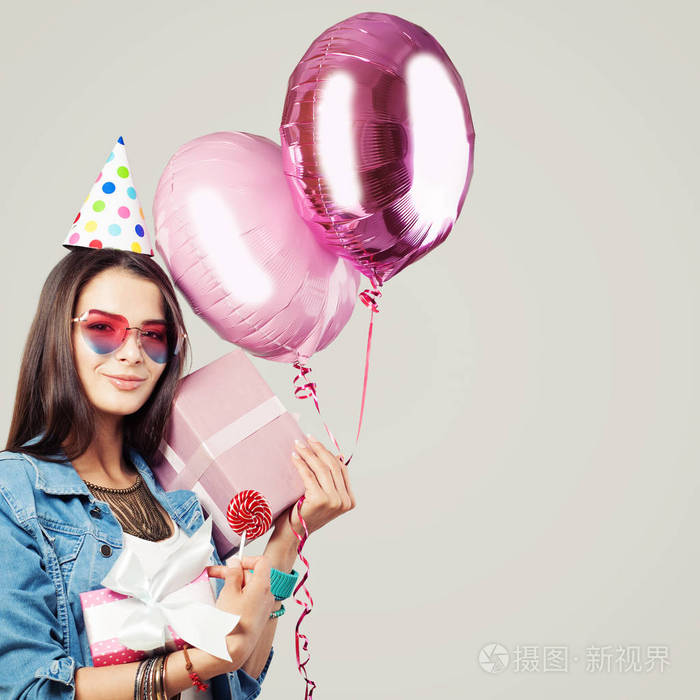 照片 美丽微笑的女人带着礼物糖果生日帽和气球.