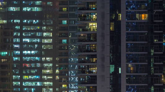夜晚时光流逝，摩天大楼的发光窗户。 迪拜码头现代住宅和写字楼高层建筑景观。 人们搬进来。 空中俯视。 右边