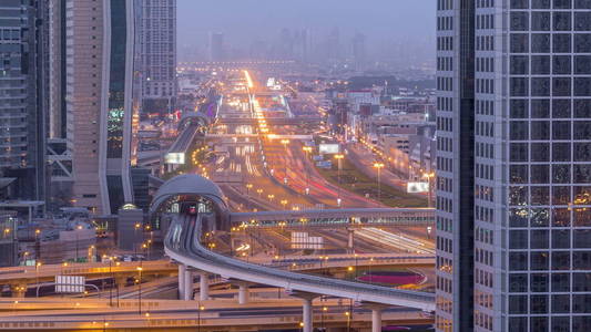 迪拜市中心天际线夜以继日过渡时间推移和谢赫扎耶德道路交叉口交通阿联酋。 从摩天大楼屋顶的鸟瞰图，有照明的现代塔楼和地铁线路