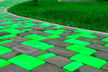 一条小径，从一个明亮的绿色瓷砖摊铺机附近的多汁的绿色草坪。 明亮的熟料瓷砖不同颜色的家。 用于瓷砖目录中的广告瓷砖制造商。