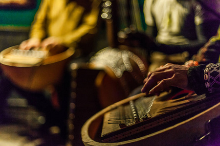 s hands playing kalimba with blurry musicians playing african in