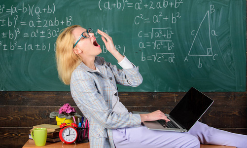 女疲惫的教师工作笔记本电脑教室黑板背景。教师的工作条件。未来教师必须考虑的工作条件。工作远远超过实际的学校一天