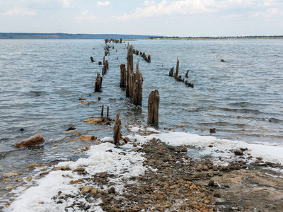 乌克兰敖德萨附近的咸河口库亚尔尼克死湖。 阳光明媚的天气，木棍倒在蓝色的水中。