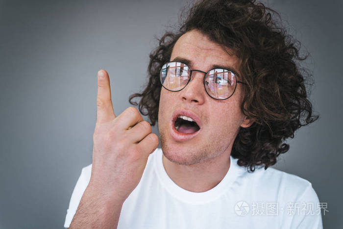 卷发的特写肖像惊讶英俊的男人有兴奋的表情向上指示手指向上的广告