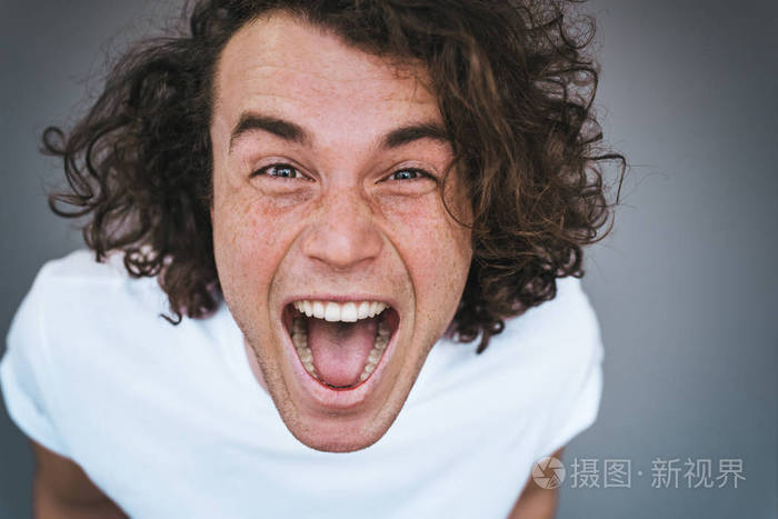 特写肖像吸引人的卷发惊讶英俊的男人有兴奋的表情张开嘴大声尖叫快乐