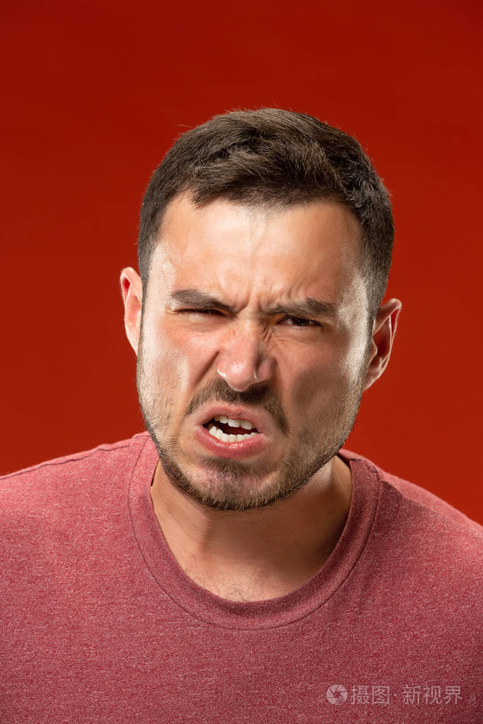 年轻的情绪愤怒的男子尖叫在红色演播室背景
