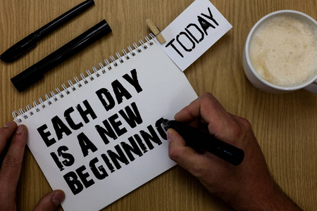 每天显示的文字标志是一个新的开始。 概念照片每天早上你可以重新开始灵感回形针保留书写记事本手握马克咖啡黑色笔木书桌