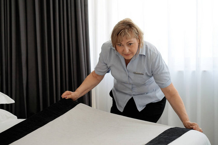 酒店房间里的女佣整理床铺。