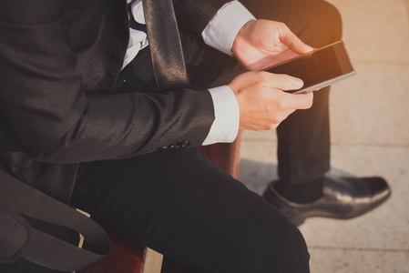 亚洲金融危机亚洲商人坐在火车站,低头看手机屏幕,感到金融危机的压力