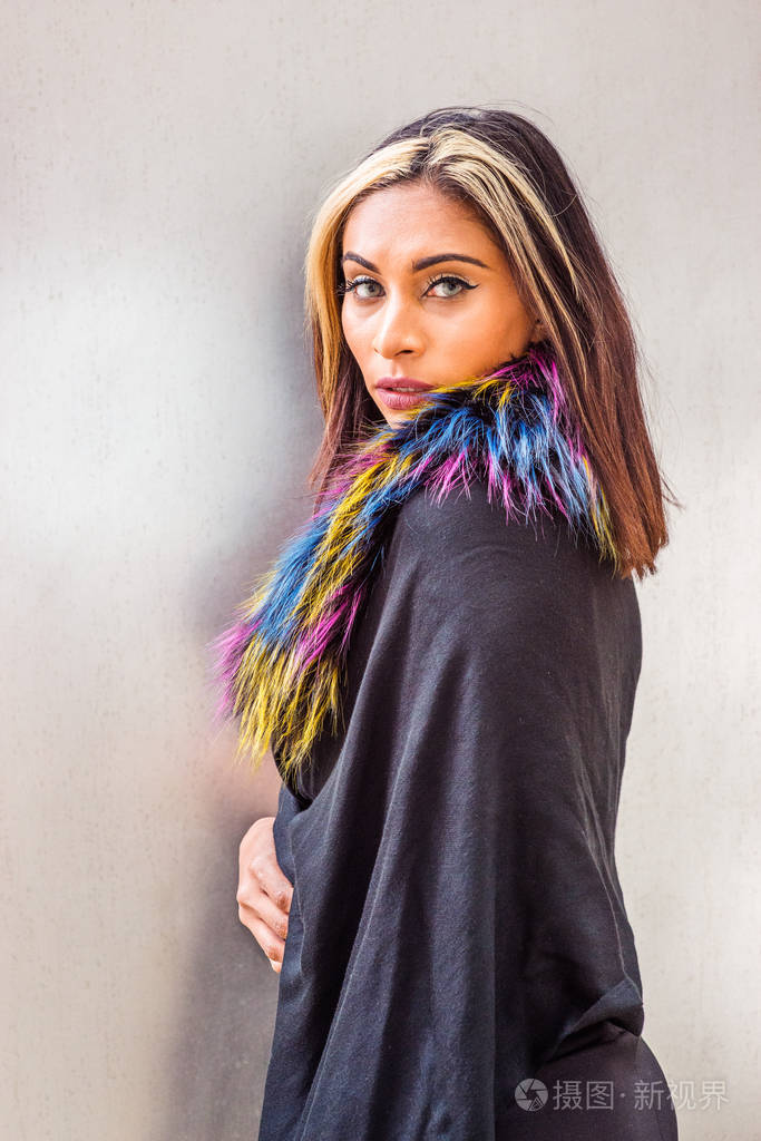 头戴黑色头发,头戴金色披肩,肩上戴着彩色人造毛皮围巾,站在银色背景