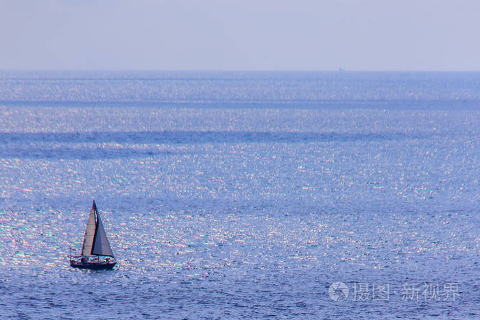 五颜六色的海洋景观，在多云的日子里，帆船靠在深蓝色的海洋下。