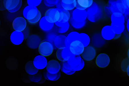 美丽的蓝色Bokeh抽象光背景。 美妙的离焦抽象蓝色圣诞节背景。 抽象的圣诞灯作为背景在夜晚与噪音颗粒和可怜的光。