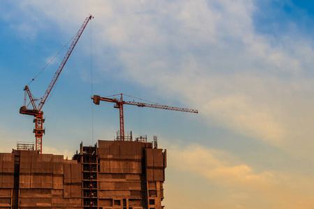 美丽的建筑塔吊轮廓与夕阳的天空背景。 建筑施工的轮廓与塔式起重机在戏剧性的天空背景下。