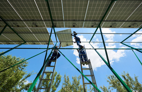 专业工人团队使用不同的设备在绿色金属结构上安装太阳能电池板。 创新的能源解决方案。 使用可再生资源。 绿色能源。