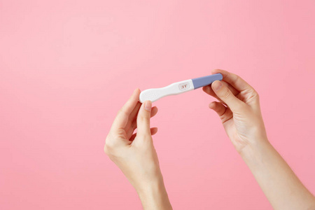 关闭女性手握怀孕试验隔离在趋势粉红色背景上。 医疗保健妇科妊娠生育产妇概念。 没有人。 复制广告