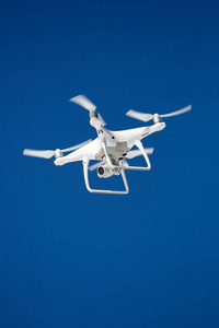空中无人机在蓝天上飞得很高。专业的四翼飞机在空中飞行。带有螺旋桨的无线机器人用于间谍和监视。从上面拍摄自然的现代设备