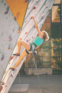 登山者训练人工浮雕。 一个女人爬上街道攀岩墙上的攀岩路线。 在大厅里训练。